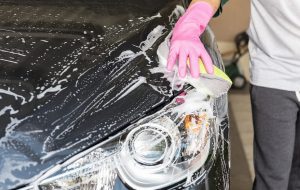 washing and waxing a car during a summer car cleaning routine