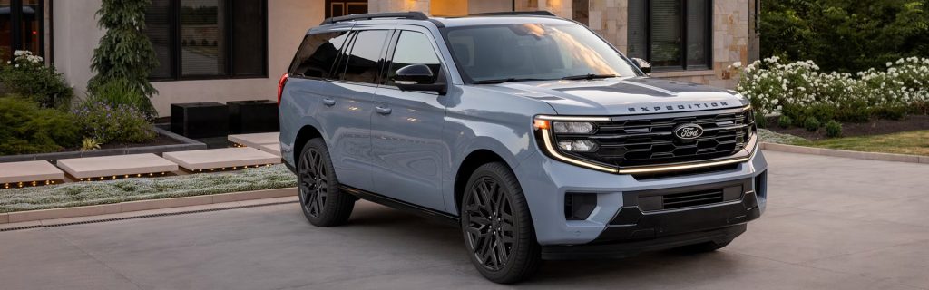 Ford Expedition SUV in light blue parked in front of a modern home, showcasing its bold front grille and spacious full-size design.