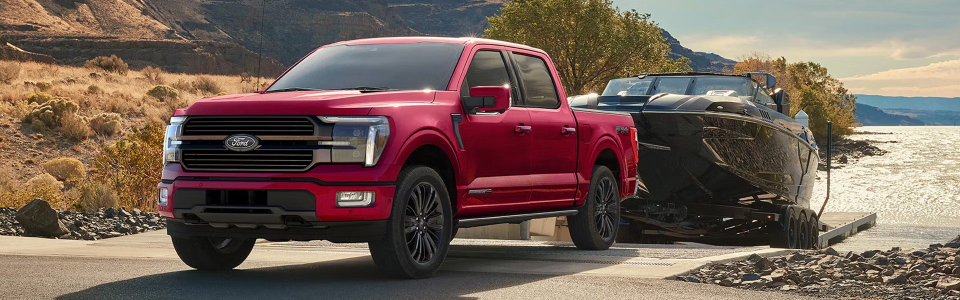 Ford F-150 pickup truck towing a boat near a lake and mountain landscape.
